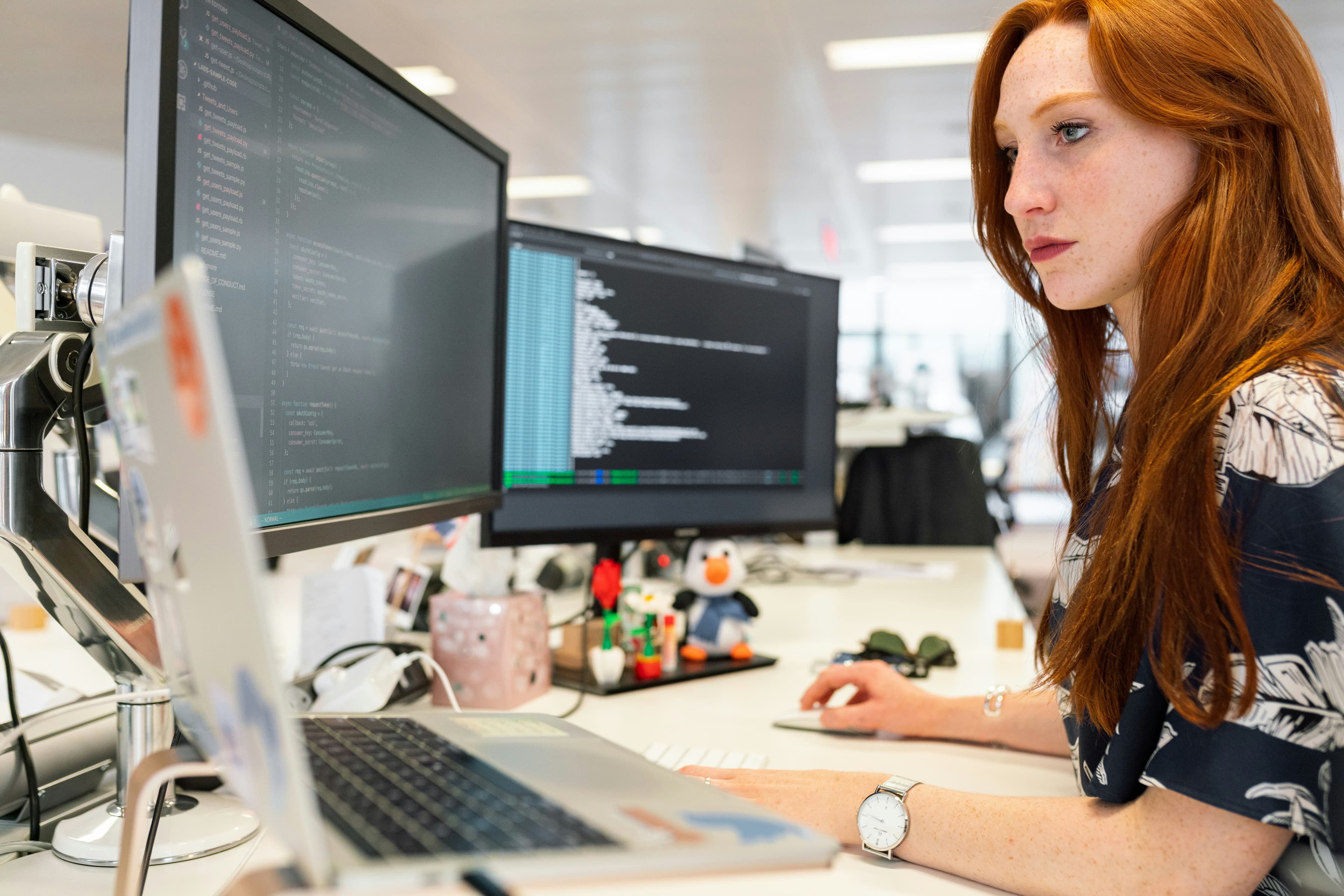 Operator working at a multi-monitor workstation, reviewing code and data.